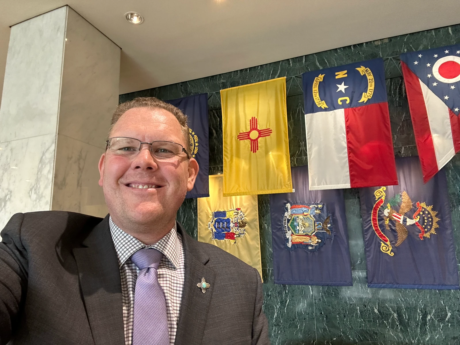 Chris Perkins beside the New Mexico state flag